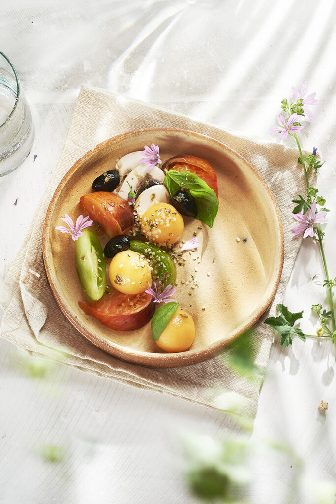 Assiette gourmande de salade estivale avec des tomates, olives, melon et champigons frais